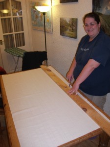 Me with my straight edge for marking fabric.  I love this straight edge: it's heavy enough that it stays put, and long enough for any fabric I'll be working with.  Here I'm using it to mark the lines I'll need for the fabric edging for the display boards Chris is making.